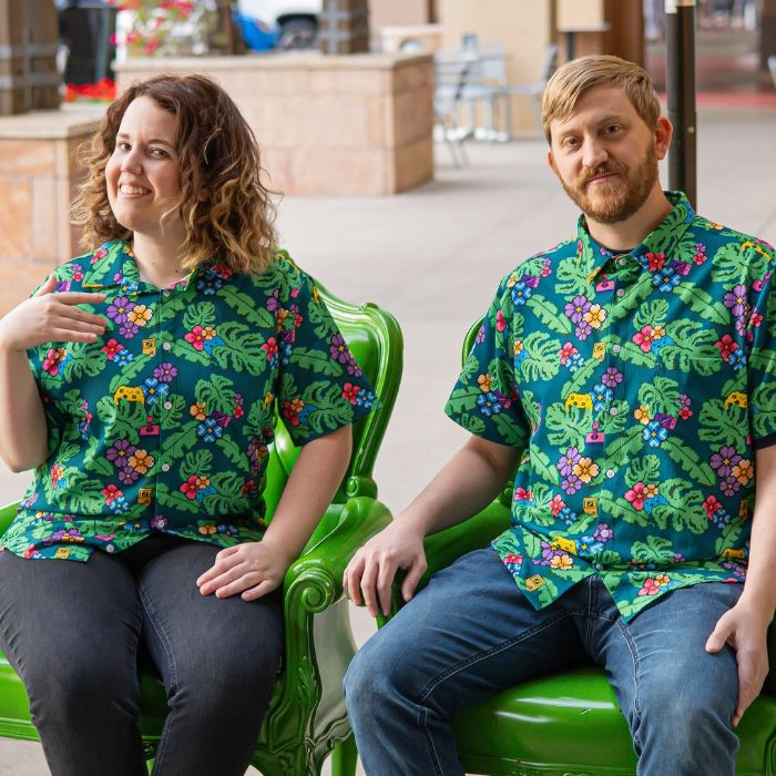 two people sitting in chairs wearing tropical Hawaiian shirts with arcade and video game symbols