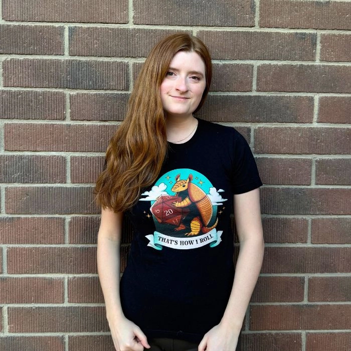 Young woman in a black graphic t-shirt standing against a brick wall